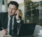 Focused businessman speaking on phone at office desk.